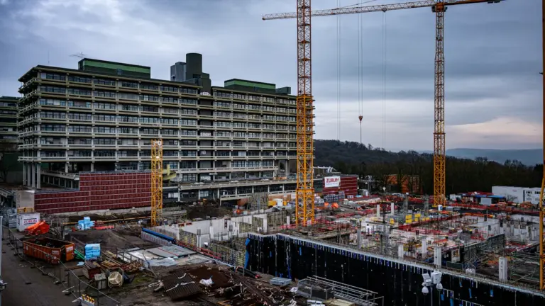 Baustelle mit Kränen und einem halbfertigen Gebäude bei trübem Wetter in Deutschland.
