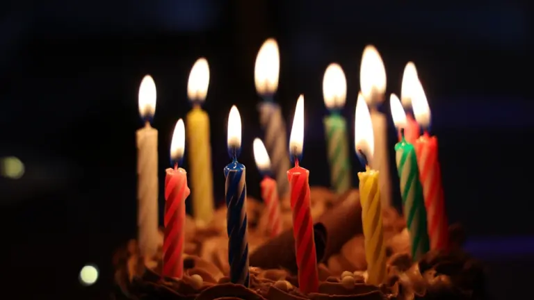 Bunte Geburtstagskerzen auf einem Schokoladenkuchen bei feierlicher Beleuchtung für einen 101. Geburtstag.